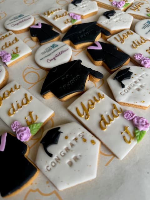 Graduation cookies with gold calligraphy and purple roses.